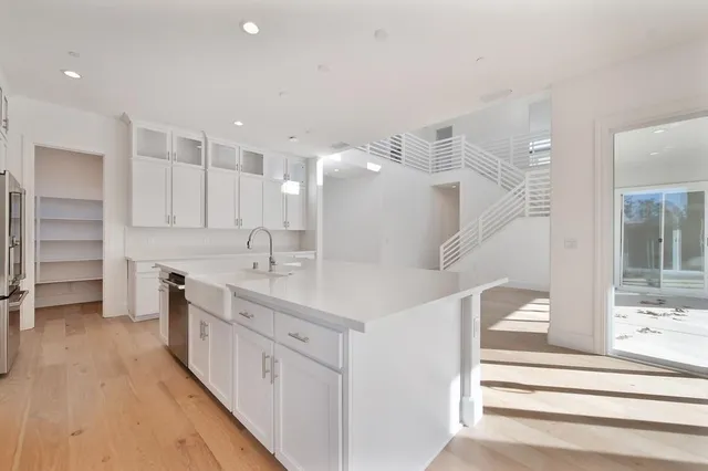 a large white kitchen with a large counter top and sink