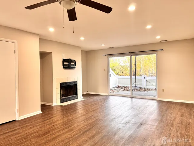 an empty room with wooden floor fireplace and windows