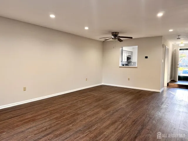 an empty room with wooden floor ceiling fan and windows