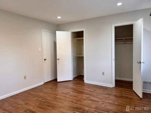 a view of an empty room with wooden floor and closet