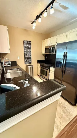 a view of a kitchen with stainless steel appliances granite countertop a sink and a stove