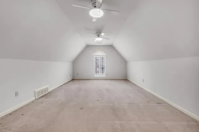 an empty room with a chandelier fan and windows