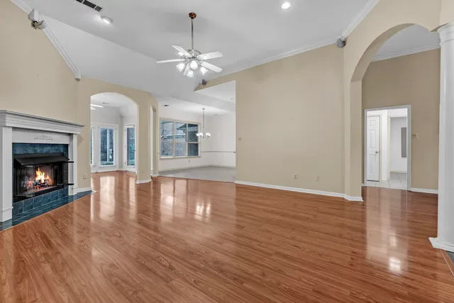 a view of an empty room with wooden floor and fireplace