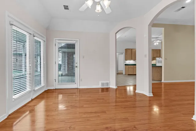 a view of an empty room with wooden floor and a window
