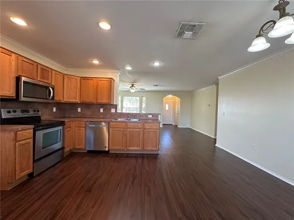 a kitchen with kitchen island granite countertop wooden floors stainless steel appliances a sink and a counter