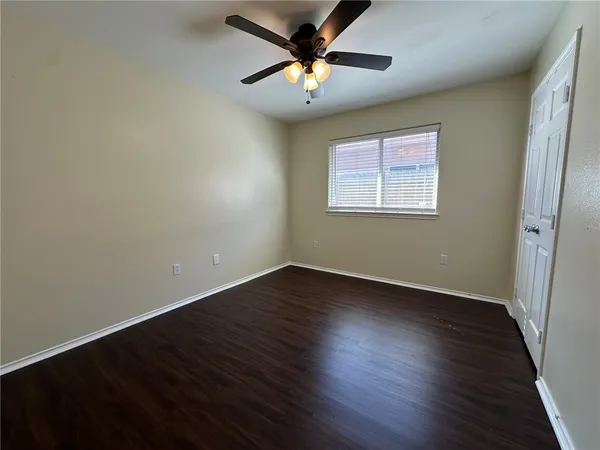 a view of an empty room with window and wooden floor