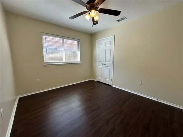 a view of an empty room with window and wooden floor