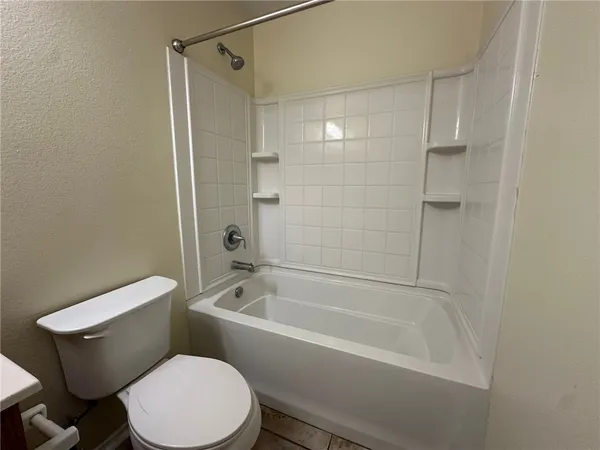 a white toilet and tub sitting next to a bathroom sink