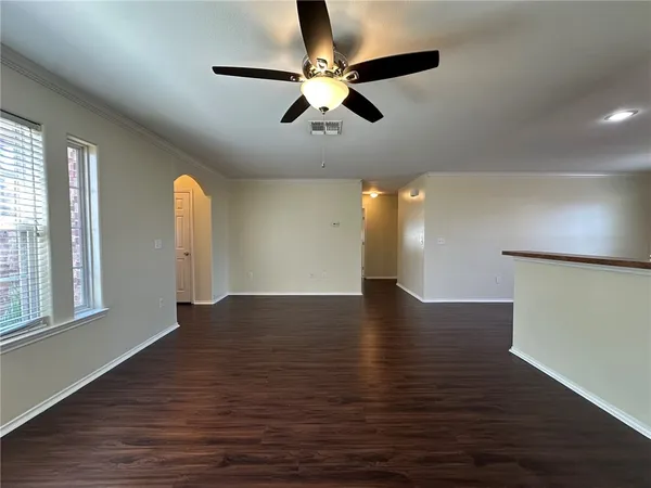 a view of an empty room with window and wooden floor