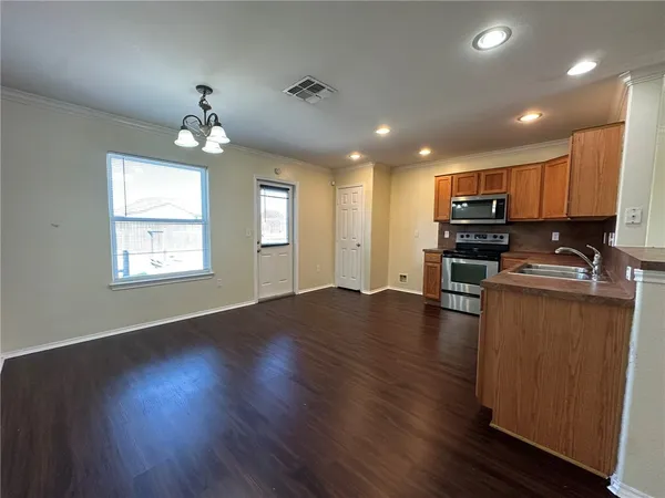 an open kitchen with wooden floor and refrigerator