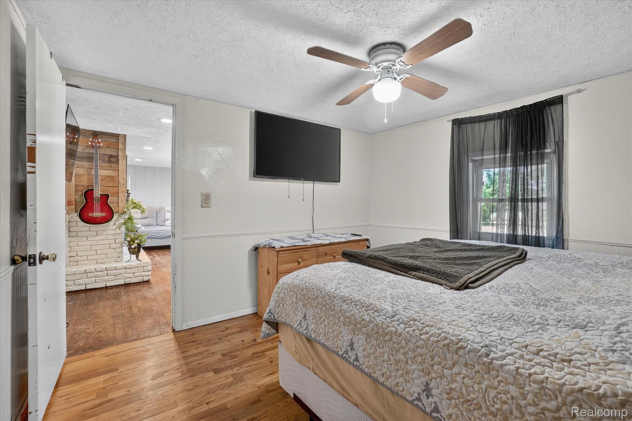 508 Deland Road Flushing, MI 48433 - Photo 18 of 38 White-painted room featuring wood-finish flooring, a ceiling fan with light, and a window with dark sheer curtains