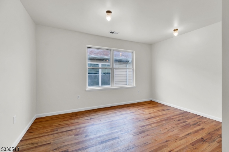 58 1st Street, Unit 3 Newark, NJ 07107 - Photo 5 of 19 a view of an empty room with wooden floor and a window