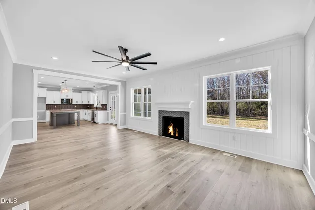 a view of an empty room with wooden floor fireplace and a window