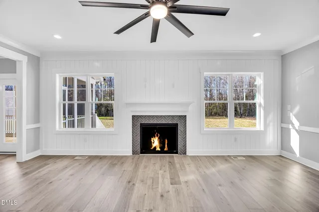 a view of a livingroom with a fireplace a ceiling fan and a kitchen