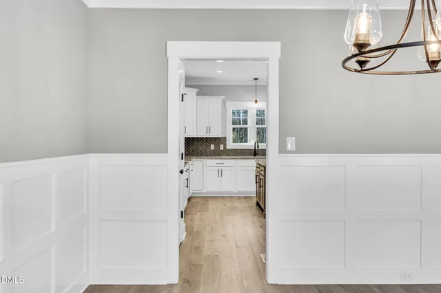 a kitchen with stainless steel appliances granite countertop a stove top oven a refrigerator a sink and white cabinets with wooden floor