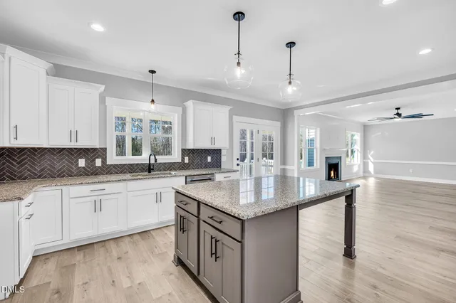 a large kitchen with granite countertop a sink and white cabinets