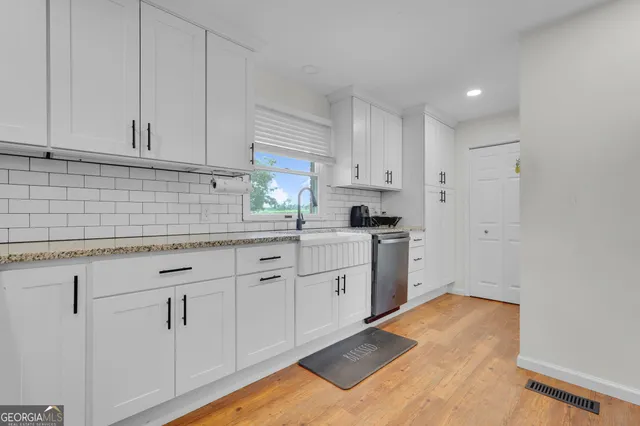 a kitchen with white cabinets and sink