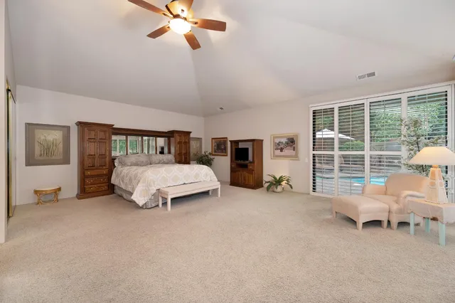 a spacious bedroom with a bed a couch and a chandelier