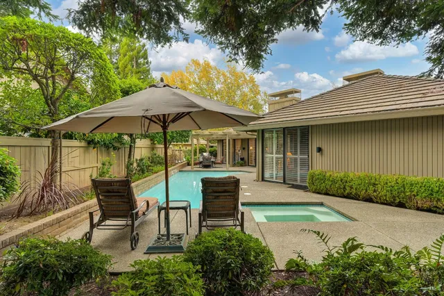 a front view of a house with a yard and a large tree