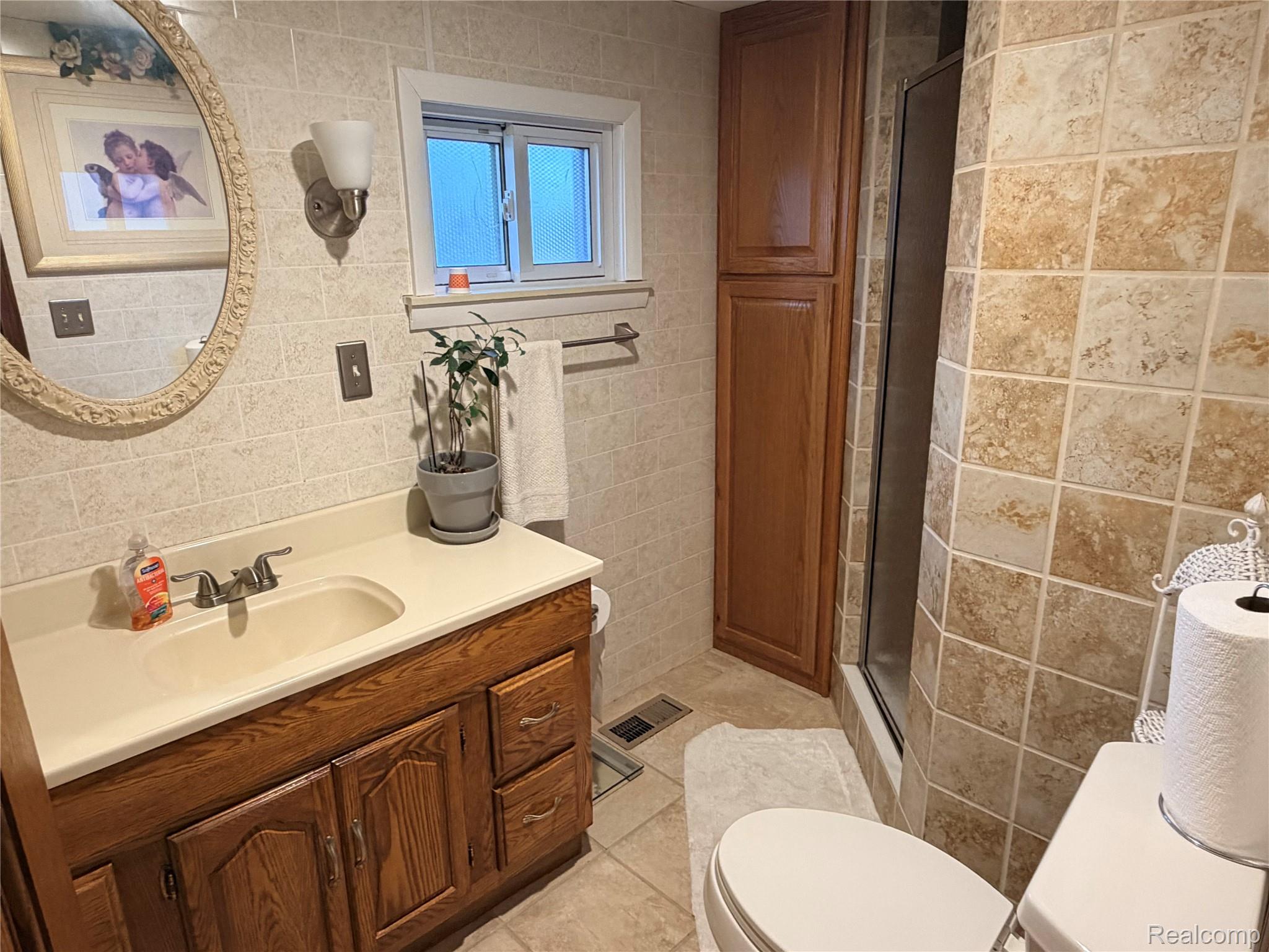 6038 Byron Road Howell, MI 48855 - Photo 14 of 24 Bathroom with tile walls, vanity, a shower stall, and light tile patterned floors