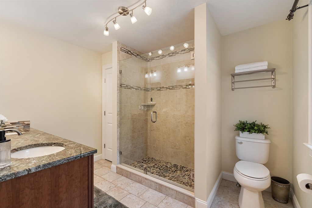 1148 Hill Road, Unit 1148 Boxborough, MA 01719 - Photo 16 of 31 a bathroom with a granite countertop sink a toilet a mirror and shower