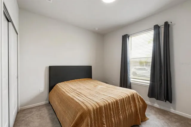 a bed sitting in a bedroom next to a window and dresser