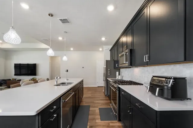 a kitchen with stainless steel appliances a sink dishwasher a stove top oven a refrigerator and island