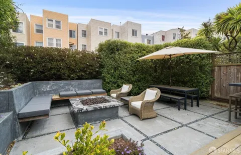 a view of a patio with couches table and chairs under an umbrella with a barbeque
