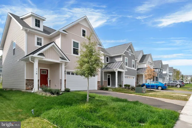 a view of a white house next to a yard with big trees
