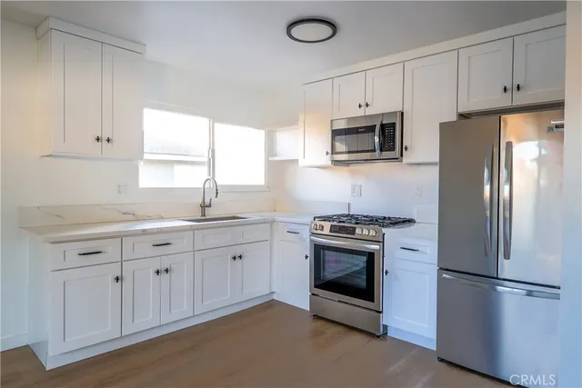 a kitchen with stainless steel appliances granite countertop a refrigerator stove a sink and dishwasher with wooden floor