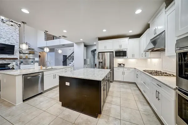 a large kitchen with stainless steel appliances granite countertop a stove top oven a sink dishwasher and a refrigerator