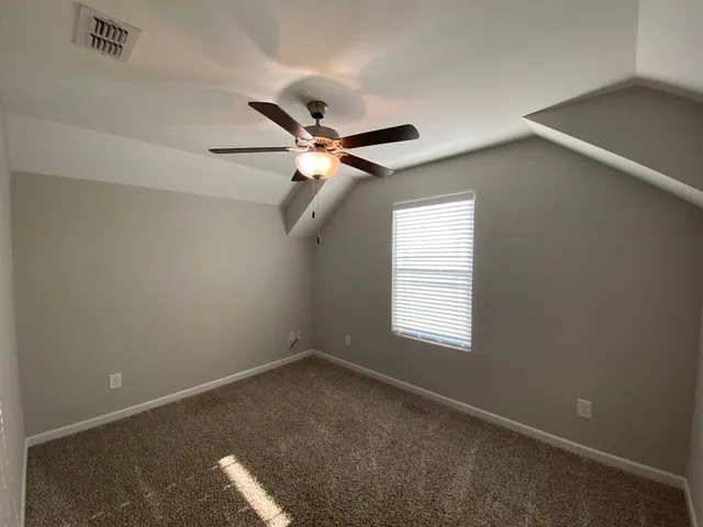 an empty room with a window and a fan