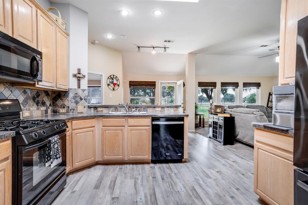 6403 Highland Crest Lane Sachse, TX 75048 - Photo 12 of 40 Kitchen with black appliances, light brown cabinets, dark countertops, and a peninsula