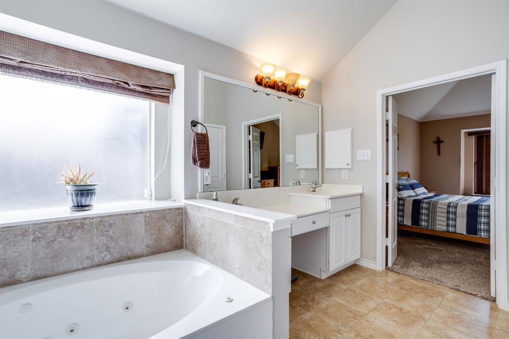 6403 Highland Crest Lane Sachse, TX 75048 - Photo 17 of 40 Bathroom featuring double vanity, connected bathroom, a tub with jets, lofted ceiling, and light tile patterned floors