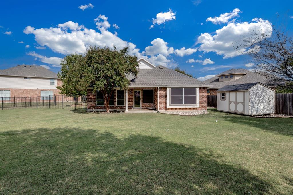 6403 Highland Crest Lane Sachse, TX 75048 - Photo 24 of 40 Rear view of house featuring a fenced backyard, a patio, a shingled roof, and brick siding