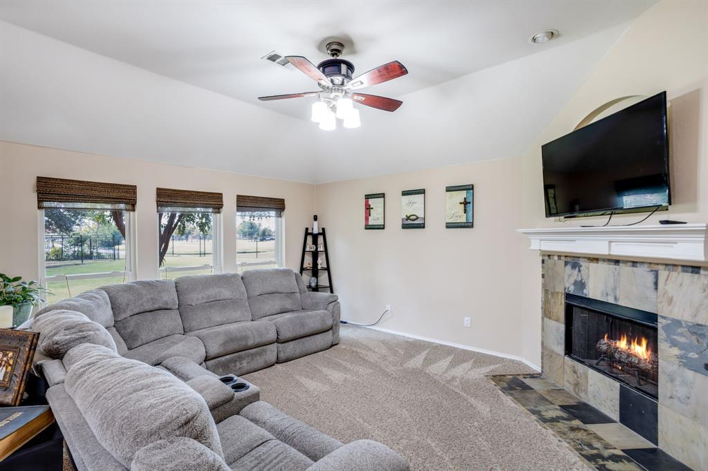 6403 Highland Crest Lane Sachse, TX 75048 - Photo 7 of 40 Carpeted living room with vaulted ceiling, ceiling fan, and a tile fireplace