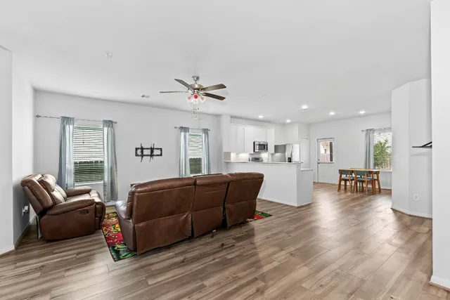 a kitchen with stainless steel appliances granite countertop a stove a refrigerator a sink a dining table and chairs with wooden floor