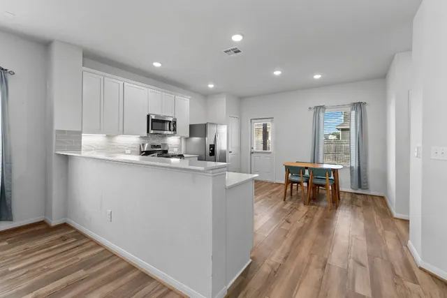 a kitchen with stainless steel appliances kitchen island granite countertop a refrigerator and a sink