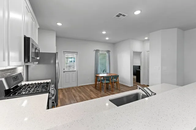 a kitchen with kitchen island granite countertop wooden floors stainless steel appliances and dining table