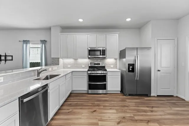a large kitchen with cabinets wooden floor and stainless steel appliances