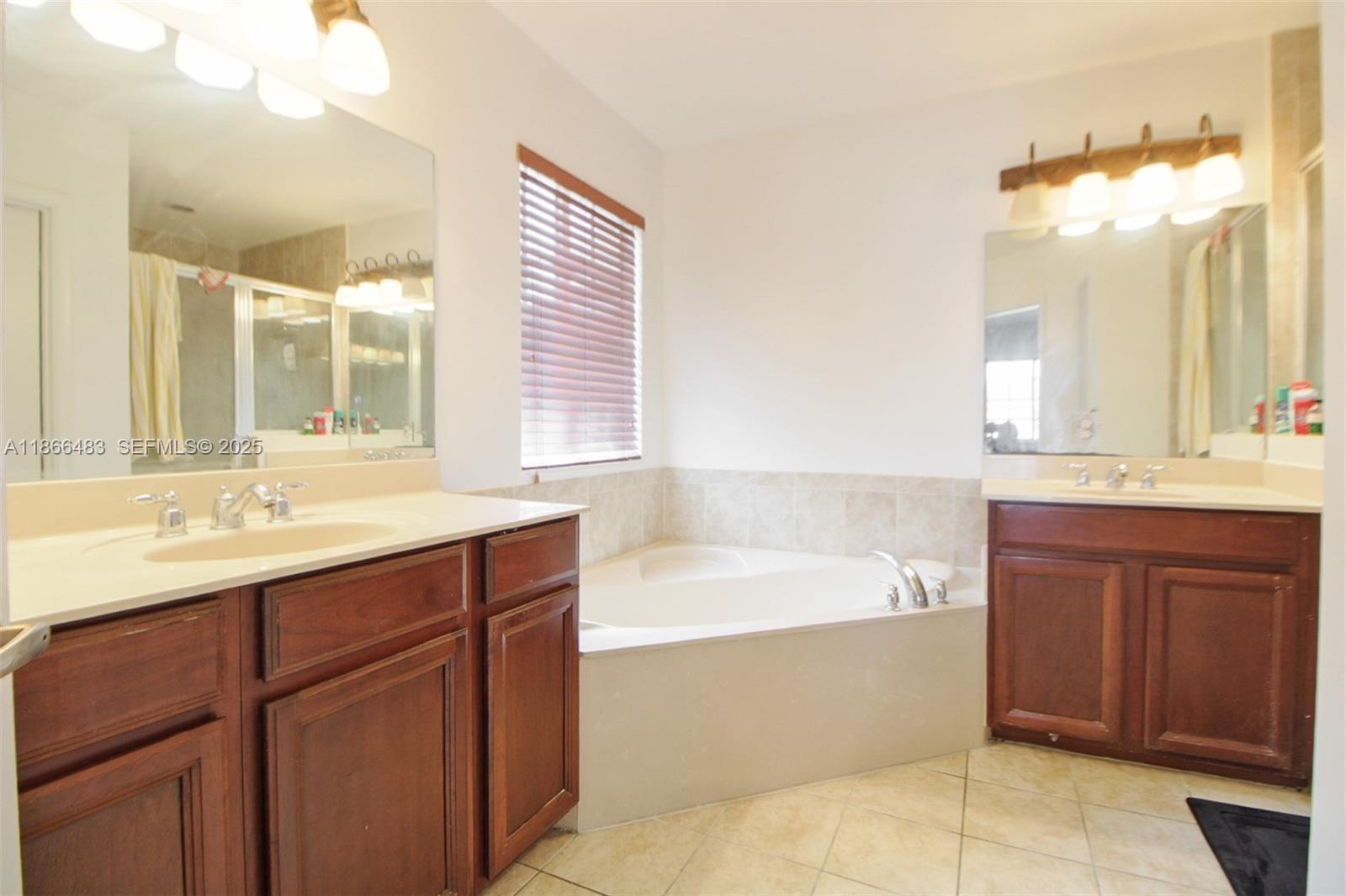 14077 Southwest 274th Terrace Homestead, FL 33032 - Photo 14 of 29 a bathroom with a bathtub sink double vanity and mirror