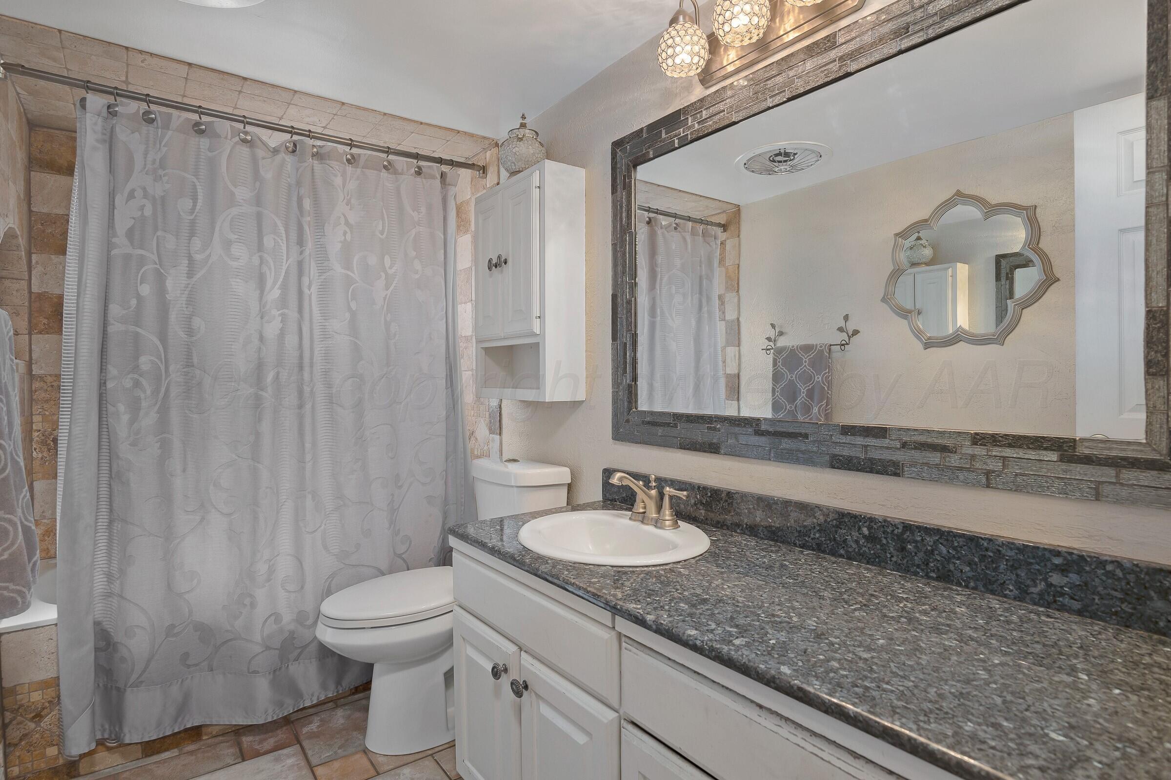 5211 Southwest 36th Avenue Amarillo, TX 79109 - Photo 13 of 22 a bathroom with a granite countertop sink and a mirror