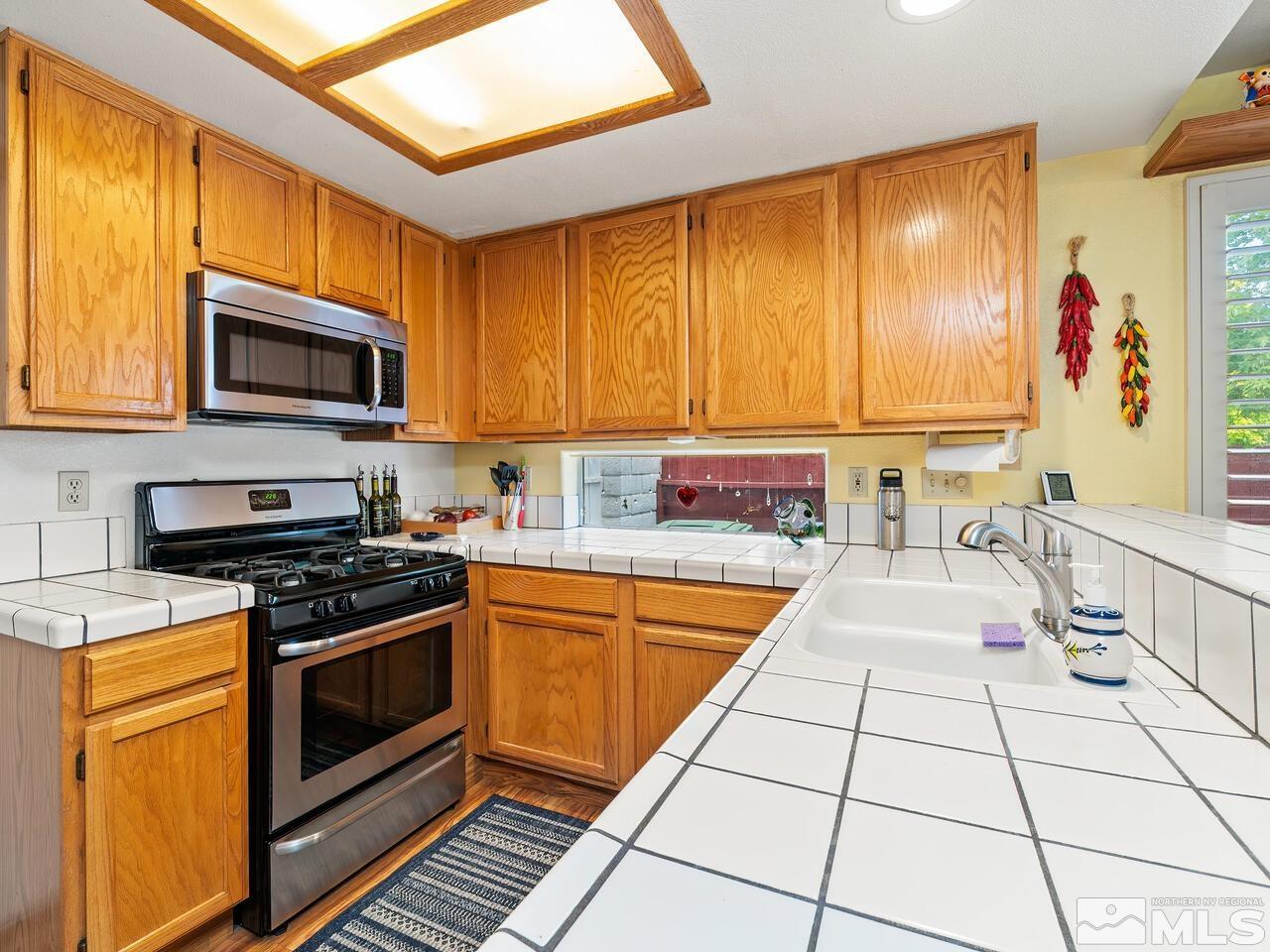7593 Whimbleton Way Reno, NV 89511 - Photo 9 of 19 a kitchen with stainless steel appliances a stove a sink and a microwave