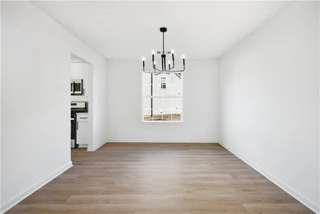 a view of an empty room with window and wooden floor