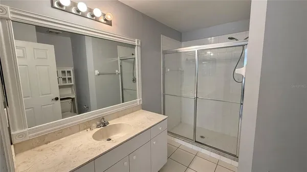 a bathroom with a granite countertop sink a mirror and shower