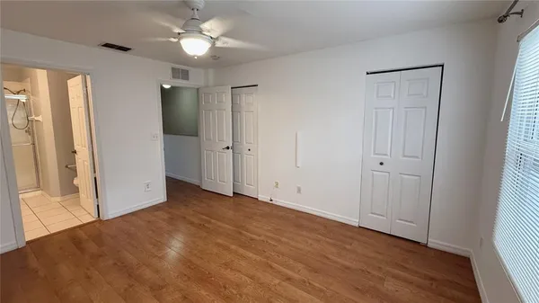 a view of empty room with wooden floor and fan