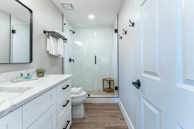 a bathroom with a sink a toilet a mirror and shower