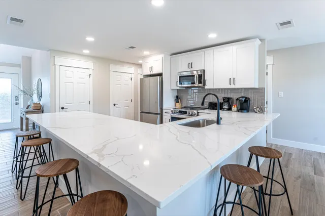 a kitchen with kitchen island a stove a table and chairs in it
