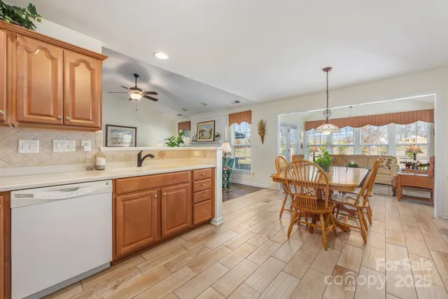 a kitchen with stainless steel appliances granite countertop table chairs sink and cabinets