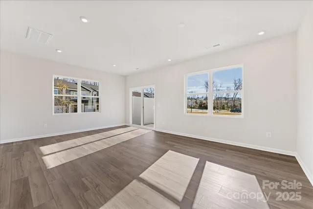 a view of an empty room with window and wooden floor